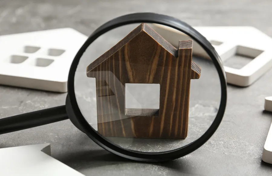 Magnifying glass over a small wooden model house
