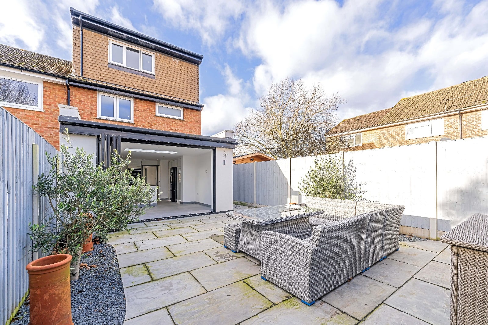 Rear of a brick house with a bifold extension and a patio