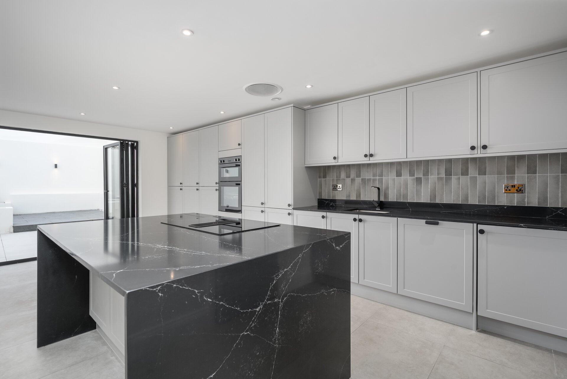 Kitchen with grey units and a dark marble-effect island