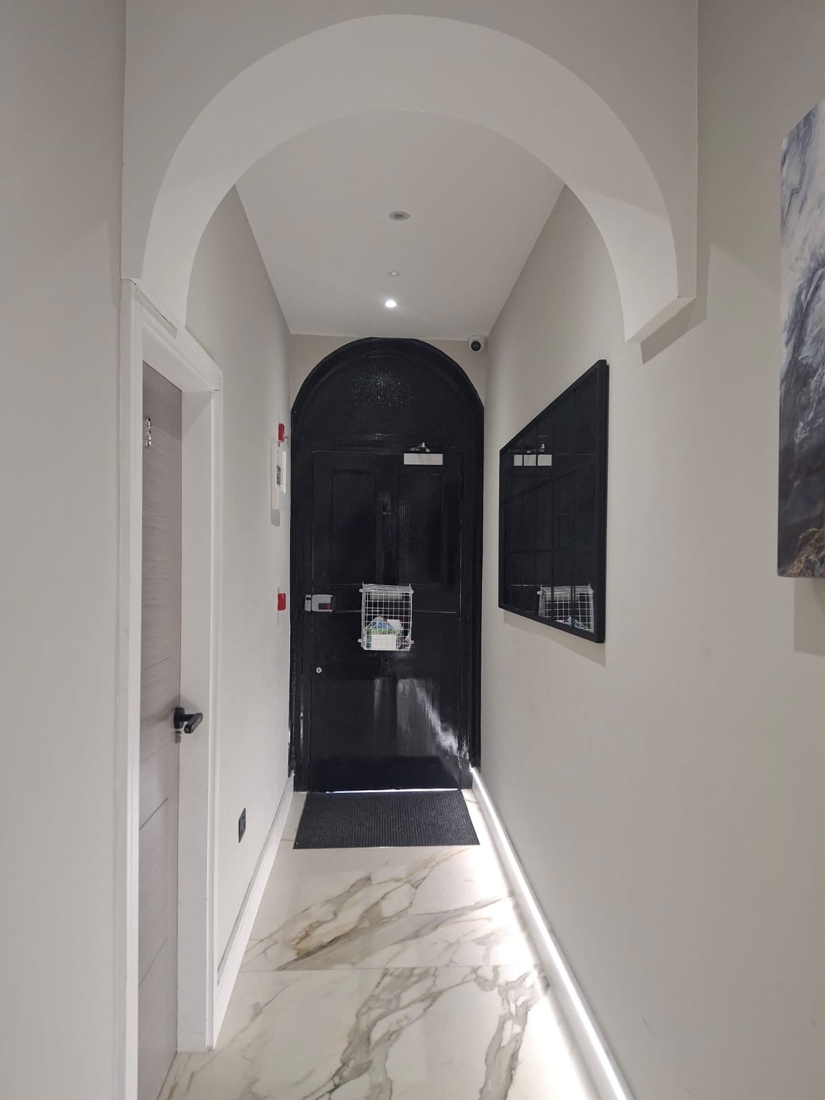 Hall with a marble-effect floor and a black arched front door