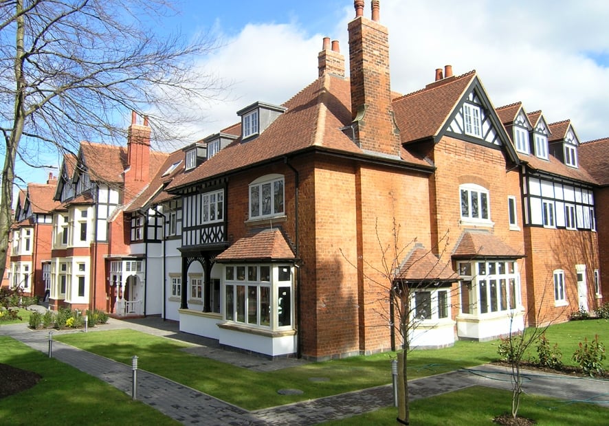 Red brick and half-timbered apartment building with bay windows and tall chimneys