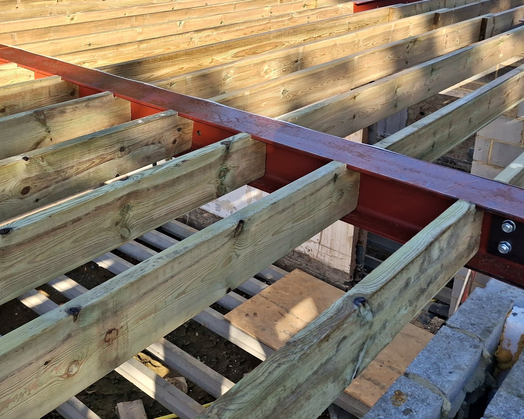 New timber floor joists fixed to a red steel beam on site